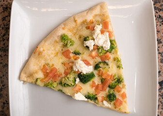 Slice of white pizza with broccoli and tomatoes 