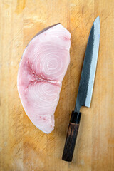 Raw and fresh sword fish steak offered with a Japanese Gyuto knife as top view on a wooden board