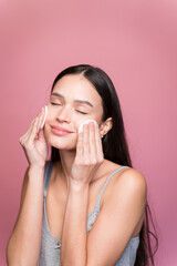 Young woman wiping makeup with absorbent cotton