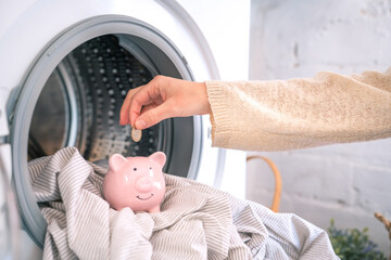 Reduce household bills expenses, money savings piggy bank. Washing machine energy electricity crisis