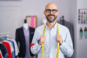 Young bald man tailor smiling confident standing at tailor shop