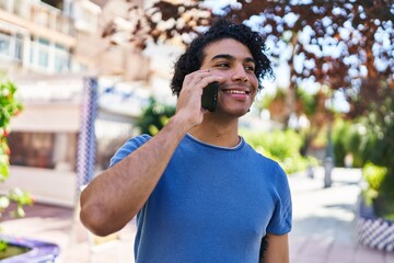Young hispanic man smiling confident talking on the smartphone at park