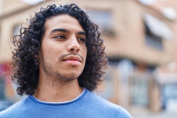 Young latin man looking to the side with serious expression at street