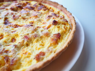 Homemade traditional french Quiche Lorraine, real recipe, white background, half view on the left side