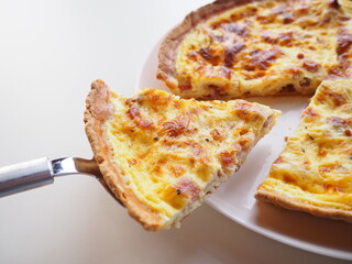Homemade traditional french Quiche Lorraine, real recipe, serving a slice, white background, space for text