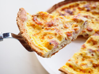 Homemade traditional french Quiche Lorraine, real recipe, serving a slice, white background
