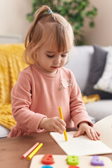 Adorable blonde girl drawing on notebook at home