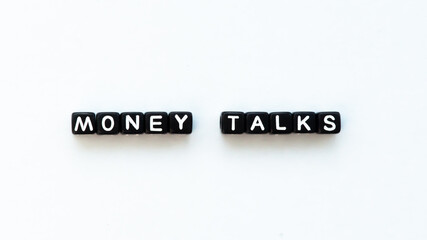 Money talks quote in black letter beads on white background. Wealth and money concept