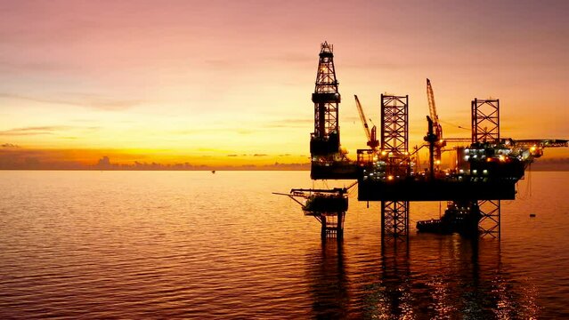 Jack up drilling rig and production platform in the middle of the ocean at sunrise time
