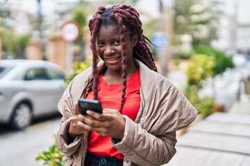 African american woman smiling confident using smartphone at street