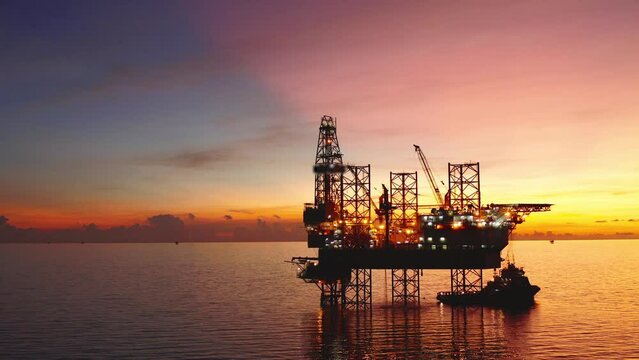 Jack up drilling rig and production platform in the middle of the ocean at sunrise time
