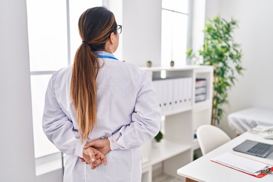 Young Beautiful Hispanic Woman Doctor Standing On Back View At Clinic