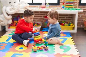 Two kids playing with hoops toy sitting on floor at kindergarten