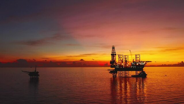 Jack up drilling rig and production platform in the middle of the ocean at sunrise time

