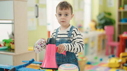 Adorable caucasian boy holding megaphone standing at kindergarten