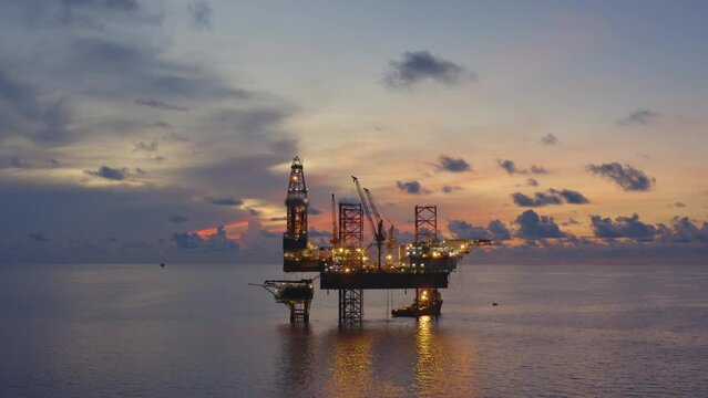 Jack up drilling rig and production platform in the middle of the ocean at sunrise time
