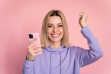 Fototapeta premium Excited woman with smartphone on pink background in studio