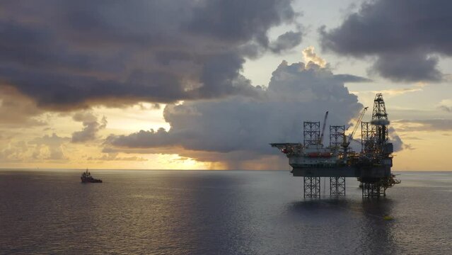 Jack up drilling rig and production platform in the middle of the ocean at sunrise time
