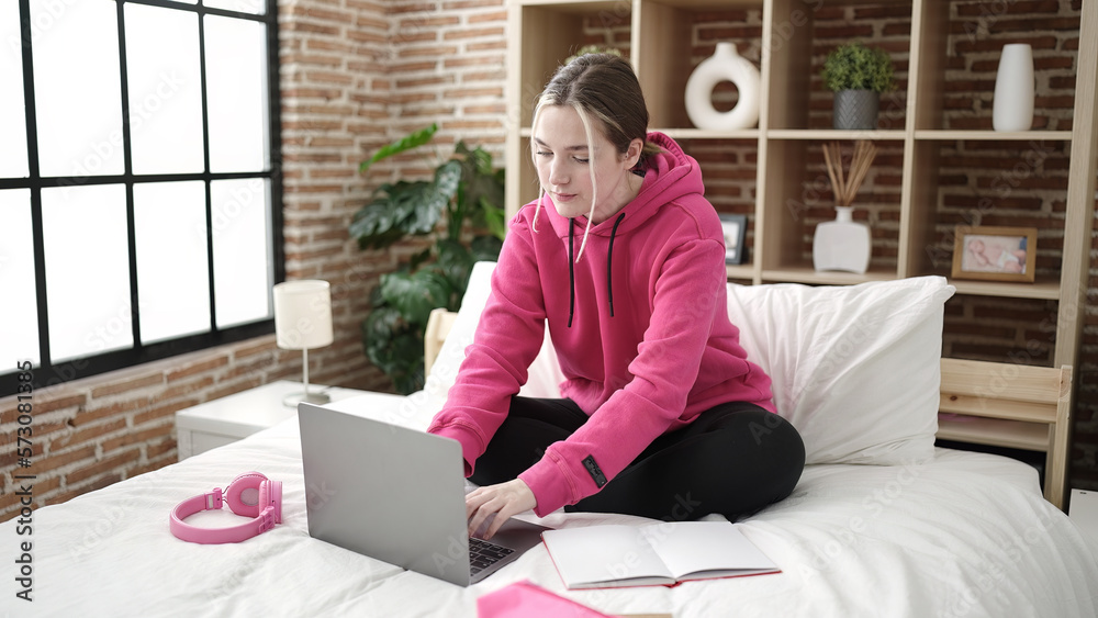 Poster Young blonde woman student using laptop studying on bed at bedroom