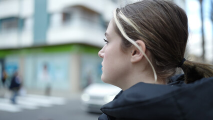 Young blonde woman looking to the side with serious expression at street