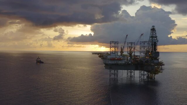Jack up drilling rig and production platform in the middle of the ocean at sunrise time
