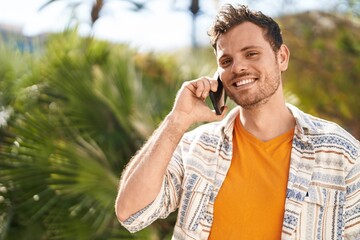 Young hispanic man smiling confident talking on the smartphone at park