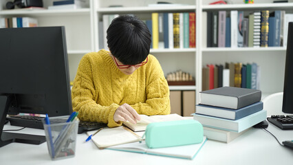 Young chinese woman student reading book studying at library university