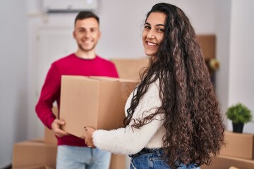 Man and woman couple holding package at new home