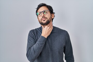 Handsome latin man standing over isolated background touching painful neck, sore throat for flu, clod and infection