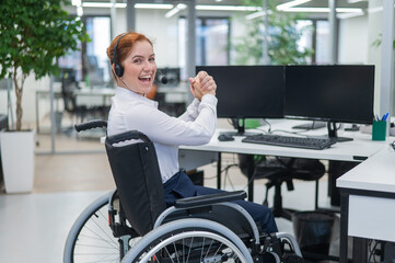 Caucasian woman with headset in a wheelchair. Happy female call center worker in the office.