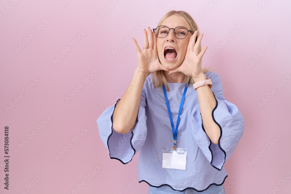 Poster Young caucasian business woman wearing id card smiling cheerful playing peek a boo with hands showing face. surprised and exited