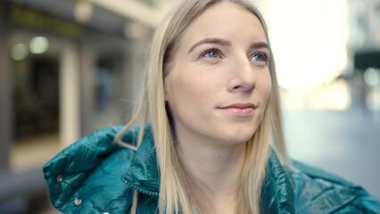 Young blonde woman standing with serious expression at street