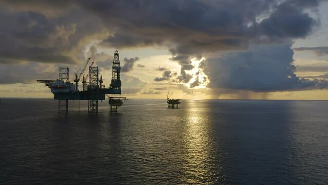 Jack up drilling rig and production platform in the middle of the ocean at sunrise time
