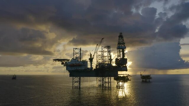 Jack up drilling rig and production platform in the middle of the ocean at sunrise time
