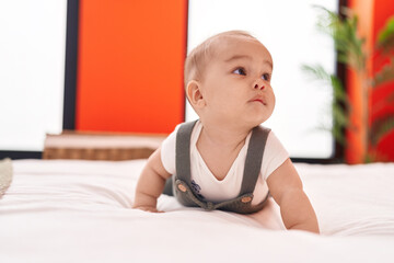 Adorable hispanic toddler lying on bed at bedroom