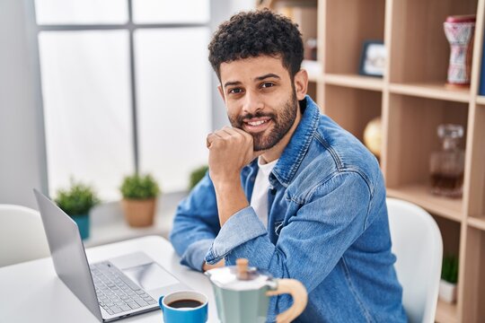 Young Arab Man Using Laptop Drinking Coffe Sitting On Table At Home