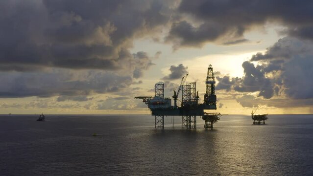 Jack up drilling rig and production platform in the middle of the ocean at sunrise time
