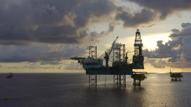 Jack up drilling rig and production platform in the middle of the ocean at sunrise time
