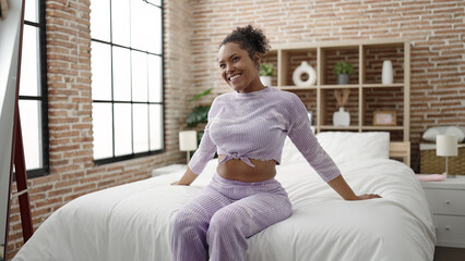 African american woman smiling confident sitting on bed at bedroom