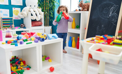 Adorable hispanic girl holding bowling pin standing at kindergarten