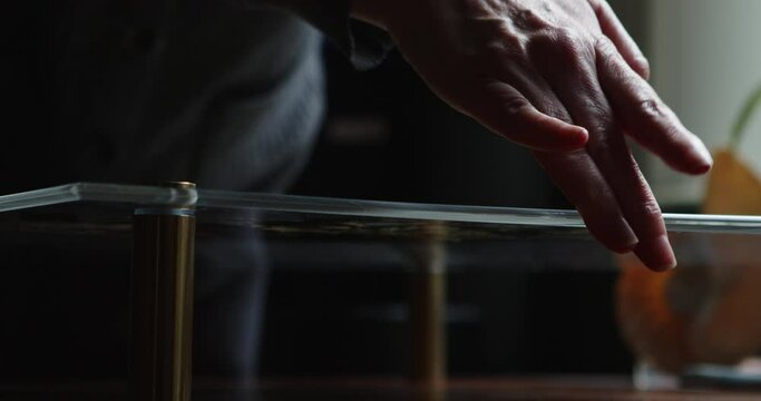 Close-up of woman's hand cleaning the surface of her pressed wedding bouquet between plexiglass 4K ProRes 422 HQ DCI 4096 x 2160.  Shot on Blackmagic Cinema Camera 6K Pro handheld, natural light  
