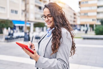 Young hispanic woman executive using touchpad standing at street