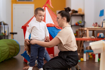 Teacher and toddler playing on circus tent sitting on floor at kindergarten