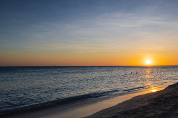 Fototapeta na wymiar Gorgeous view of orange sunset on sandy beach of Eagle Beach in Atlantic Ocean on Aruba island.