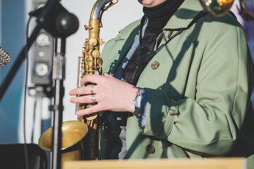 Fototapeta premium Concert view of a female saxophonist, professional saxophone player with vocalist and musical during jazz band orchestra performing, young girl musician