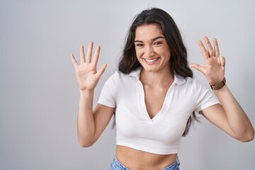Young teenager girl standing over white background showing and pointing up with fingers number nine while smiling confident and happy.