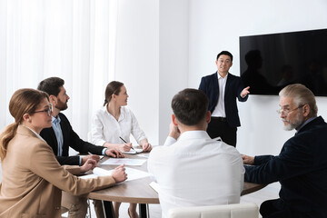 Business conference. Group of people listening to speaker report near tv screen in meeting room