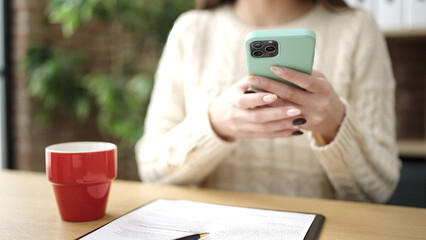 Young beautiful hispanic woman business worker using smartphone drinking coffee at office