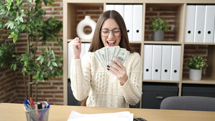 Young beautiful hispanic woman business worker counting dollars with winner expression at office