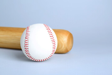 Wooden baseball bat and ball on light grey background, space for text. Sports equipment